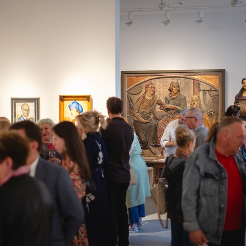 Tłum ludzi zwiedza galerię sztuki i ogląda obrazy.